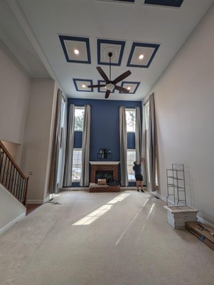 Grand Living Room Ceiling Transformation - This project involved a stunning ceiling transformation to elevate the elegance of a spacious living room. The original ceiling design was reimagined with custom geometric coffered panels, creating a visually striking and sophisticated focal point. A carefully curated color palette of deep blue and crisp white added contrast and depth, enhancing the room’s grandeur.

The installation process included detailed trim work, recessed lighting integration, and a sleek ceiling fan to complement the modern aesthetic. The final result not only enhances the architectural beauty of the space but also improves lighting distribution and overall ambiance.

From planning to execution, our team ensured precision and quality craftsmanship to bring this vision to life. This transformation showcases our expertise in high-end ceiling design, making a bold statement in home interiors.