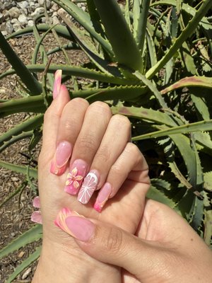 Floral-Inspired Theme: Blush Bloom - This look features a soft pink base with a glossy finish, accented by hand-painted floral and citrus-inspired designs. The 3D flower adds a delicate touch of dimension, while the gradient swirls and tiny water droplet details create a fresh, tropical vibe. Perfect for summer, vacations, or anyone wanting a chic pop of color with a classy finish. Floral-Inspired Theme: Blush Bloom - This look features a soft pink base with a glossy finish, accented by hand-painted floral and citrus-inspired designs. The 3D flower adds a delicate touch of dimension, while the gradient swirls and tiny water droplet details create a fresh, tropical vibe. Perfect for summer, vacations, or anyone wanting a chic pop of color with a classy finish.