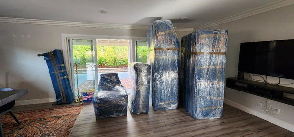 Prepping a living room for loading - This showcases our wrap and stack methods. Our movers will blanket wrap a living room, moving all the items to one place to prepare it to be loaded on to the truck. Our highly experienced loader will move on to the truck and start to stack all the items in the truck, carefully and strategically.