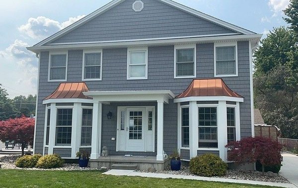 Complete Exterior Transformation – Modern Elegance with Durable Finishes - This comprehensive exterior renovation project showcases our expertise in transforming a home, garage, and shed into a cohesive and stylish property. We began by removing outdated corbels, crown moldings, and siding to prepare the surfaces for a fresh, modern look. The upgrade included:

Custom white aluminum-wrapped 1x8 columns with elegant 10.5" bases.
White perimeter hidden vent soffits for improved ventilation and a clean aesthetic.
Precision-installed wood trim (3.5" on sides/rear, 2" on the front) for all windows and doors.
Charcoal Gray CertainTeed Cedar Impressions Perfection Straight Edge 7" vinyl siding for a stunning, durable finish.
White aluminum trim on fascia, rake boards, and window casings for a polished, seamless look.
18 sets of black or slate louvered shutters to enhance curb appeal.
Additionally, we installed new seamless white 6" gutters with hidden hangers, sturdy downspouts, and ShurFlo leaf protection for optimal water management. The project includes a 5-year labor warranty and a limited lifetime warranty on materials per manufacturer specifications.

Let us bring your vision to life with expert craftsmanship and lasting results!