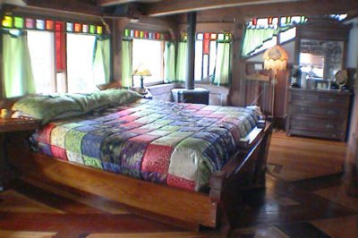 Historic Farmhouse Rooms - Second floor of the Carriage House, queen bed, large skylights over the bed, handcrafted redwood wainscoting below blue Victorian wallpaper, separate entrance via balcony which is private with views of the mountains and creek. Private microwave, refrigerator, kitchen area just outside room. Opens out into library with wood stove and living room. Private Bath.