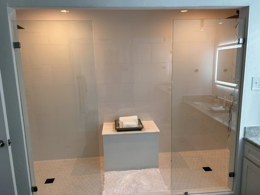 Modern bathroom suite - At the heart of the suite is a large walk-in double shower, featuring dual rainfall showerheads, a built-in bench, and smart temperature controls, ensuring a spa-like experience. Dramatic black or white marble adorns the shower walls, creating a striking contrast with minimalist fixtures in matte black, polished chrome, or brushed gold.
The flooring and countertops are wrapped in dramatic marble, elevating the space with natural veining and high-gloss finishes. The countertops stretch across a custom vanity with integrated sinks, offering a seamless, floating aesthetic. Understated LED lighting illuminates the space, casting a soft glow beneath the vanity and around mirrors framed in sleek metal. Modern bathroom suite - At the heart of the suite is a large walk-in double shower, featuring dual rainfall showerheads, a built-in bench, and smart temperature controls, ensuring a spa-like experience. Dramatic black or white marble adorns the shower walls, creating a striking contrast with minimalist fixtures in matte black, polished chrome, or brushed gold.
The flooring and countertops are wrapped in dramatic marble, elevating the space with natural veining and high-gloss finishes. The countertops stretch across a custom vanity with integrated sinks, offering a seamless, floating aesthetic. Understated LED lighting illuminates the space, casting a soft glow beneath the vanity and around mirrors framed in sleek metal.