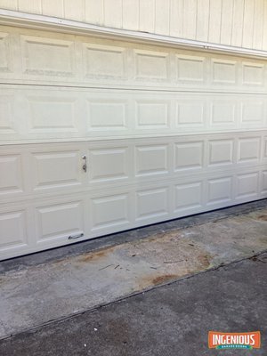 Cracked Bottom Sections on a Sugar Land Garage Door: Two New Sections, Springs and Lock, February 2026 - The homeowner said it looked like someone had hit the door, and you could see daylight through the bottom. A car was stuck inside. It turned out to be worn springs, not an impact.

This door had no opener and was lifted by hand every day. Steve found the springs were no longer holding tension, so the door was far heavier than it should be. Years of heaving it up by the bottom had cracked the bottom two sections along the seams until they buckled. The rollers were old and jamming, and the lock was broken, so the garage could not be locked.

The top two sections were still in good shape, so this was a repair, not a new door. We installed new bottom and intermediate C.H.I. sections in almond, a new pair of torsion springs, a full set of nylon rollers, and a new keyed lock with a locking bar.

A note on color: new sections come in the same factory almond, but sun-faded original panels may not match exactly. If a perfect match matters, the door can be painted afterward.

If your door feels heavy or slides back down when you let go halfway, the springs are worn. Fixing them early saves the sections.