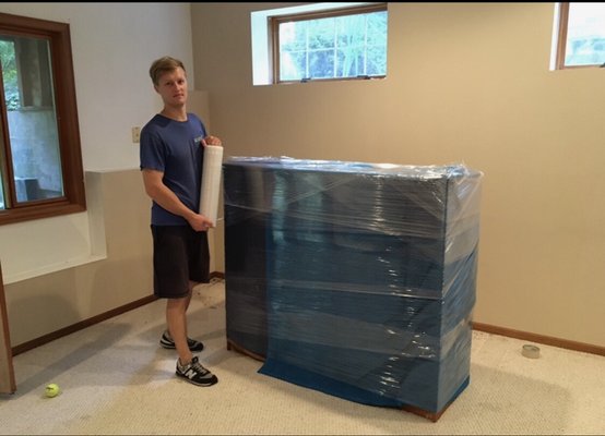Securely Wrapped Dresser: Protected with Blankets and Plastic Wrap for a Safe Move - A dresser carefully wrapped in soft, padded blankets and secured with plastic wrap, each drawer and handle protected to prevent scratches, scuffs, or dust. Corners and edges are gently cushioned, ensuring the dresser stays in pristine condition throughout the move. This thoughtful wrapping keeps the dresser safe and ready for a seamless arrival at its new home. Securely Wrapped Dresser: Protected with Blankets and Plastic Wrap for a Safe Move - A dresser carefully wrapped in soft, padded blankets and secured with plastic wrap, each drawer and handle protected to prevent scratches, scuffs, or dust. Corners and edges are gently cushioned, ensuring the dresser stays in pristine condition throughout the move. This thoughtful wrapping keeps the dresser safe and ready for a seamless arrival at its new home.