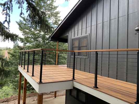 Cumaru Hardwood Decks with Custom Railing from ViewRail - Our customers had a home in the hills of Cascade that needed an exterior facelift.  They had multiple decks and sets of stairs that were constructed of redwood and needed to be replaced.  DBS and the homeowners designed the new decks and stairs to be more up-to-date with a sleek, contemporary look.  We used Cumaru hardwood, also known as Brazilian Teak, because it exceeds the requirements for a Class A fire rating, making it an exceptional choice for mountain homes.  It is a very popular hardwood due to its density, which makes it extremely resistant to termites and decay.  Cumaru is an attractive, medium golden-brown color with shades of tan, which results in a tonal warmth that creates a beautiful, relaxing outdoor living area.
In keeping with the contemporary look, the owners chose to use a railing system from ViewRail.  It is constructed with 3” x 3” posts and ¼” horizontal rods in matte black, resulting in an unobstructed view of the gorgeous Colorado scenery.  We also added a drink cap in Cumaru.  All the attention to detail creates a fantastic set of decks that the homeowners will be using to enjoy the mountain scenery for years to come!