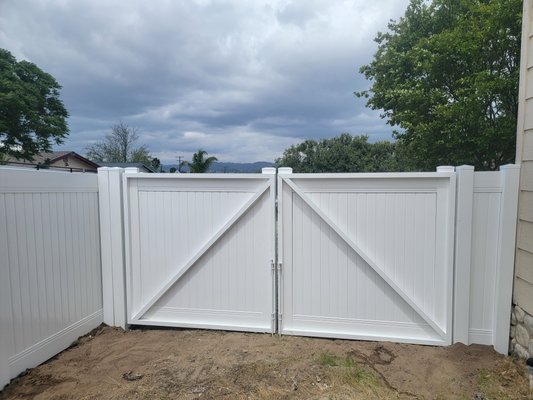 RV gate with white steel frame - This vinyl privacy fence was added around the perimeter of the property with an RV gate