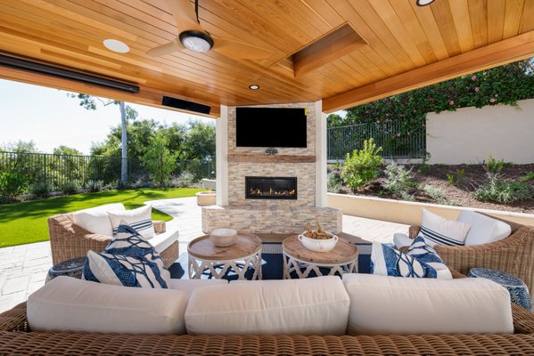 California Outdoor Living in Rancho Santa Margarita - California rooms are an open-air transition room, usually serving as a seamless extension of a home's great room or dining area. It is a place where a homeowner can both unwind or entertain guests and is quickly becoming one of the most popular design trends. These homeowners, in Rancho Santa Margarita, hit the mark by creating a luxurious experience, tailor made for quiet contemplation and family entertainment.

As part of a whole home remodel, the downstairs Family Room provides a cohesive flow into a stunning 534 square foot California Room. Aluminum, multi sliding glass doors open up to a massive indoor/ outdoor living space, reminiscent of a family room. Stamped concrete decorative stones in limestone, marble and granite were used contiguously, detailing fine craftsmanship in the flooring. 
Inspired by nature, two stone pillars add texture in mixed shades of ‘Deserto Naturo’ porcelain tiles. One pillar features a built-in, switch operated, gas fireplace and a spot for a large TV above. The other pillar features a unique Alfresco gas pizza oven as well as a gas BBQ and beverage fridge. Vinyl accordion-style kitchen windows open all the way to allow for easy pass through over a white quartz Caesarstone countertop with additional seating. 

The showstopper in this luxurious addition might just be the drop-dead-gorgeous tight-knot cedar ceiling. This insect resistant ceiling includes 3 skylights, 2 fans, 2 radiant heaters, built-in speakers and perfectly placed recessed lighting. If you look closely, you can also spot a hidden, remote operated, drop-down projector screen including a theater projector hiding in a little wooden box above the entryway. 

Sea Pointe Design & Remodel also helped with the interior design for this project, selecting all soft goods and furnishings, tying everything together like a dream!

If you’re planning your own California Room or Outdoor Transitional Living remodel in Rancho Santa Margarita or any other home remodeling project in Orange County, Sea Pointe Design & Remodel has you covered! We’ve been meeting the remodeling needs of Orange County residents for over 35 years and we’d love to remodel YOUR home next. Simply give us a call at (949) 749-5642 to schedule your complimentary design consultation.