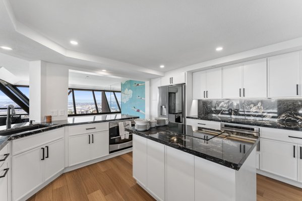Luxury High-Rise Kitchen Remodeling with Custom Finishes by PBH Builders in San Diego, CA - This kitchen remodeling project in San Diego, CA was completed by PBH Builders for a high-rise condominium with panoramic city and bay views. The original kitchen was boxed in with dark cabinetry, granite countertops, and outdated tile flooring that made the space feel disconnected from the rest of the home.
We saw an opportunity to reshape the layout and bring a more modern, open feel to the space. By removing the upper cabinets and bulky soffits, we opened up the lines of sight and allowed natural light to flow throughout the kitchen. This created a stronger connection between the kitchen, the living area, and the sweeping views just outside.
The new design features white cabinetry with matte black hardware, complemented by black stone-look countertops and a full-height backsplash. A custom island with a built-in cooktop provides added functionality and anchors the room. Warm-toned wide-plank flooring runs throughout, tying the space together and adding balance to the bold finishes.
This remodel reflects the clean, modern aesthetic the homeowners wanted while making better use of the home’s natural light and layout.
Thinking about updating your kitchen? Let PBH Builders build a space that truly works for how you live. Luxury High-Rise Kitchen Remodeling with Custom Finishes by PBH Builders in San Diego, CA - This kitchen remodeling project in San Diego, CA was completed by PBH Builders for a high-rise condominium with panoramic city and bay views. The original kitchen was boxed in with dark cabinetry, granite countertops, and outdated tile flooring that made the space feel disconnected from the rest of the home.
We saw an opportunity to reshape the layout and bring a more modern, open feel to the space. By removing the upper cabinets and bulky soffits, we opened up the lines of sight and allowed natural light to flow throughout the kitchen. This created a stronger connection between the kitchen, the living area, and the sweeping views just outside.
The new design features white cabinetry with matte black hardware, complemented by black stone-look countertops and a full-height backsplash. A custom island with a built-in cooktop provides added functionality and anchors the room. Warm-toned wide-plank flooring runs throughout, tying the space together and adding balance to the bold finishes.
This remodel reflects the clean, modern aesthetic the homeowners wanted while making better use of the home’s natural light and layout.
Thinking about updating your kitchen? Let PBH Builders build a space that truly works for how you live.