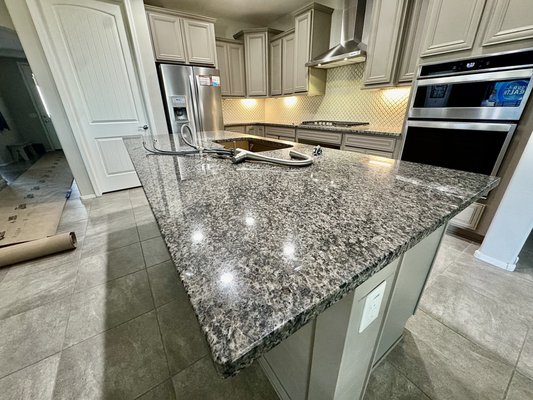 Tichawa Residence Kitchen Renovation - The Tichawa couple reached out to us looking give a different look to their kithcen. They specified to us their desire to brighten up their kitchen by replacing their dark and outdated granite countertop for something much more brighter and elegant. They were guided through various options and were able to find the exact piece they were looking for. A very beautiful polished Luxor quartz stone in white with very elegant touches of taupe veining. Alongside new countertop the Tichawas also added a new undermounted 18 gauge stainless steel sink that just tied in the whole project. Some goodies for their cabinets were also added, as they wished to add new handles for their doors and drawers, and new soft-close hinges for their doors as well! Tichawa Residence Kitchen Renovation - The Tichawa couple reached out to us looking give a different look to their kithcen. They specified to us their desire to brighten up their kitchen by replacing their dark and outdated granite countertop for something much more brighter and elegant. They were guided through various options and were able to find the exact piece they were looking for. A very beautiful polished Luxor quartz stone in white with very elegant touches of taupe veining. Alongside new countertop the Tichawas also added a new undermounted 18 gauge stainless steel sink that just tied in the whole project. Some goodies for their cabinets were also added, as they wished to add new handles for their doors and drawers, and new soft-close hinges for their doors as well!