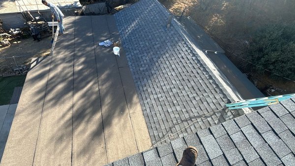 Roof Replacement - Roof replacement in progress and completed: existing tile roofing was removed and staged on-site (tiles stacked across the roof) for safe haul-away. The deck was prepped and covered with new underlayment across the main slopes, with crews installing new flashing/details as needed. Final photos show the finished roof sections with new gray shingles and clean transitions to the adjacent low-slope/flat roof area.