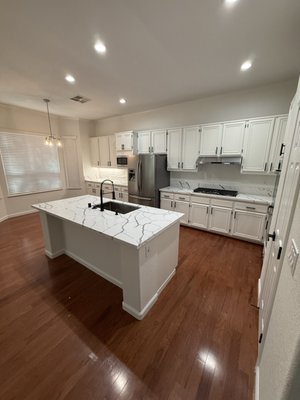 Complete Modern Kitchen Remodel & Open Concept Island Transformation - Complete kitchen transformation designed for modern living, improved flow, and high functionality.

Scope of work completed in this remodel:
• Full demolition of outdated honey oak cabinetry, old tiled countertops, and the restrictive peninsula layout.
• Reconfigured the space with a custom center island featuring premium Calacatta quartz countertops with dramatic veining and an undermount sink.
• Installed full-height, soft-close white shaker cabinets paired with sleek matte black pulls and hardware.
• Added under-cabinet task lighting and energy-efficient recessed LED ceiling lights to brighten the entire kitchen.
• Integrated a clean, modern subway tile backsplash and updated plumbing with a high-arc matte black pull-down faucet.
• Installed water-resistant luxury flooring seamlessly connecting the kitchen to the rest of the living space.

Looking to remodel your kitchen? Contact Premier Constructions today for a free on-site consultation and estimate!