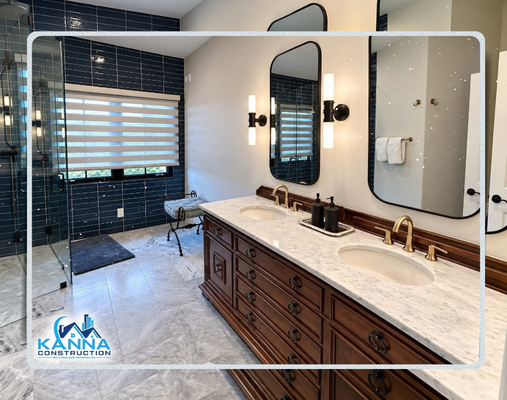 La Jolla | Luxury Primary Bathroom - Transformed an existing layout into a spa-like retreat featuring high-end fixtures, custom tilework, and a blend of classic warm wood and sleek modern accents. Built by Kanna Construction, this project combines bold design choices with timeless, functional craftsmanship.
Custom Double Vanity: Rich, furniture-style dark wood cabinetry with ornate drawer details, paired with a classic white marble countertop and dual undermount sinks.
Statement Wall Tile: Deep navy blue subway accent tile running floor-to-ceiling in the shower and window nook, creating a striking contrast against neutral walls.
Modern Fixtures & Lighting: Brushed brass classic widespread faucets complemented by matte black pill-shaped vanity mirrors and modern vertical tube sconces.
Walk-In Glass Shower: Seamless frameless glass shower enclosure with continuation of the feature tile and pristine marble-look porcelain floor tile throughout.
Thoughtful Details: Integrated window blinds for privacy and light control, alongside coordinated matte black and brass bath accessories.
Ready to elevate your home with a luxury bathroom renovation or custom ADU en-suite? Contact Kanna Construction today to start planning your dream project! La Jolla | Luxury Primary Bathroom - Transformed an existing layout into a spa-like retreat featuring high-end fixtures, custom tilework, and a blend of classic warm wood and sleek modern accents. Built by Kanna Construction, this project combines bold design choices with timeless, functional craftsmanship.
Custom Double Vanity: Rich, furniture-style dark wood cabinetry with ornate drawer details, paired with a classic white marble countertop and dual undermount sinks.
Statement Wall Tile: Deep navy blue subway accent tile running floor-to-ceiling in the shower and window nook, creating a striking contrast against neutral walls.
Modern Fixtures & Lighting: Brushed brass classic widespread faucets complemented by matte black pill-shaped vanity mirrors and modern vertical tube sconces.
Walk-In Glass Shower: Seamless frameless glass shower enclosure with continuation of the feature tile and pristine marble-look porcelain floor tile throughout.
Thoughtful Details: Integrated window blinds for privacy and light control, alongside coordinated matte black and brass bath accessories.
Ready to elevate your home with a luxury bathroom renovation or custom ADU en-suite? Contact Kanna Construction today to start planning your dream project!